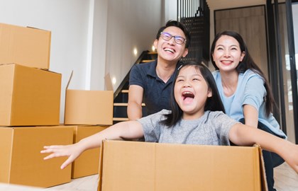 Family of Asian descent with moving boxes in new home