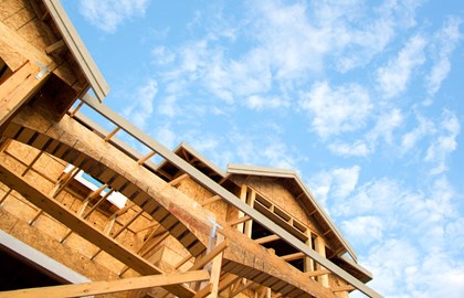 Wooden frame of a new house under construction with blue sky beyond